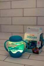 The Blue Mini Sensory Jar and Silicone Fun Filler lit up on a counter.
