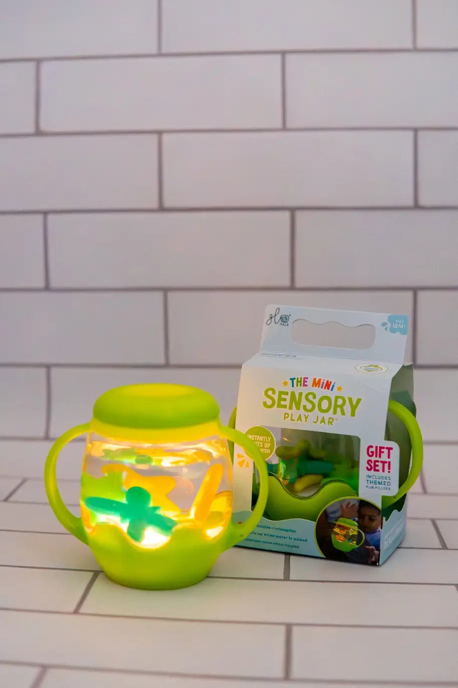 The Glo Pals Green Mini Sensory Jar and Silicone Fun Filler lit up on a counter.