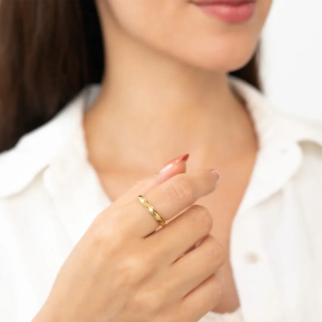 A hand models the Gold Dainty Hammered Band Spinning Fidget Ring.