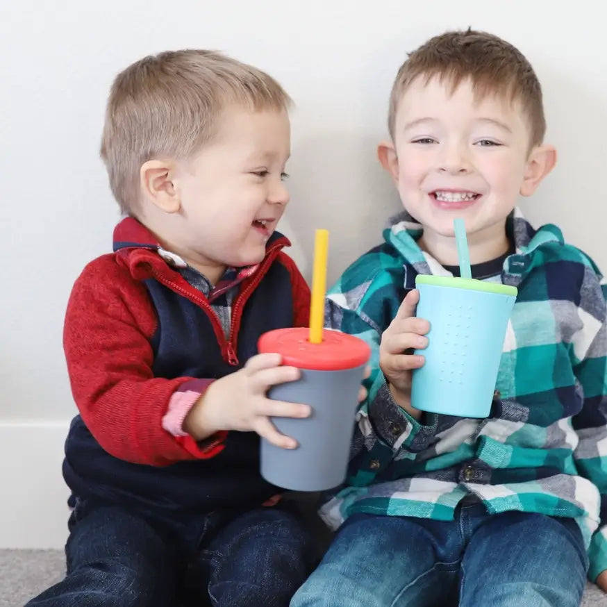 Two children hold two different 12 oz Silicone Straw Kids Cups. 