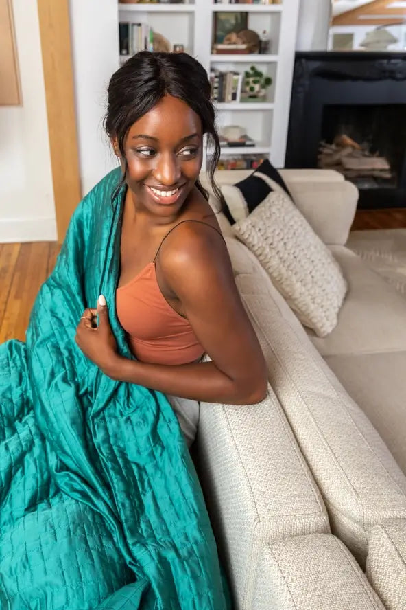 A woman snuggles up with the Forest Green 20 lb Gravity Cooling Weighted Blanket.