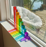 The 10-Piece Crystal Clear Pyramid Lucite Blocks arranged tallest to smallest, reflecting colorful light from the window.