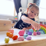 A child plays with the 16-Piece Wooden Balancing Stones Stacking Blocks.