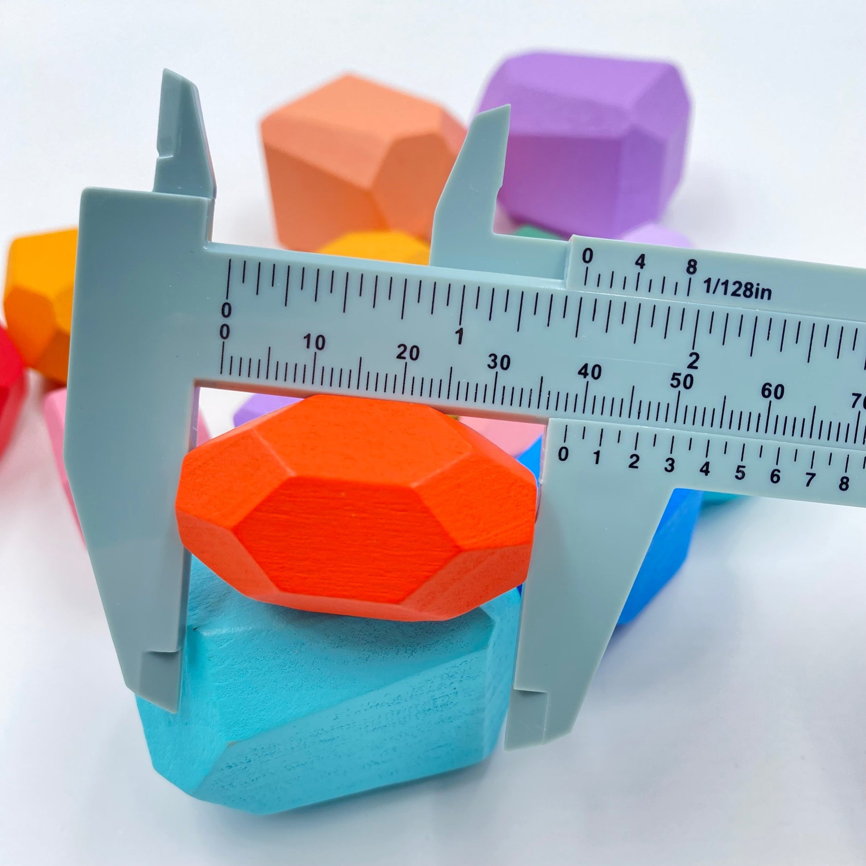 An Orange Wooden Balancing Stones Stacking Block being measured by a blue tool.