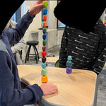 A child stacks 13 of the 16 Wooden Balancing Stone Stacking Blocks on top of each other.