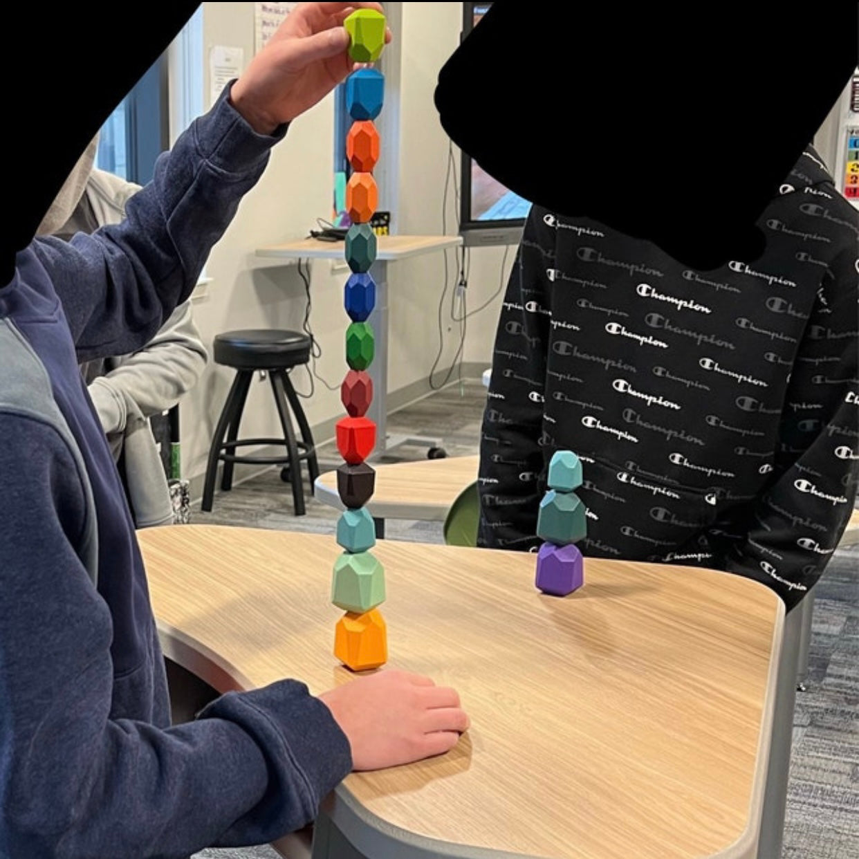 A child stacks 13 of the 16 Wooden Balancing Stone Stacking Blocks on top of each other.