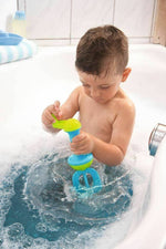 A child uses the HABA Bubble Bath Whisk in Blue in a bath tub full of bubbles.