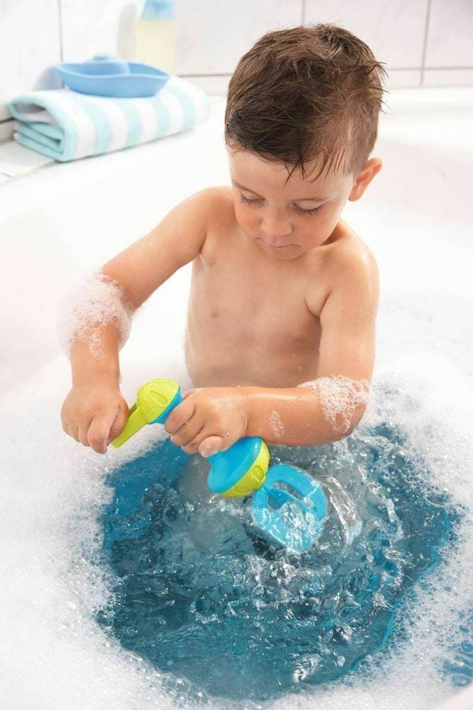 A child uses the HABA Bubble Bath Whisk in Blue in a bath tub full of bubbles.