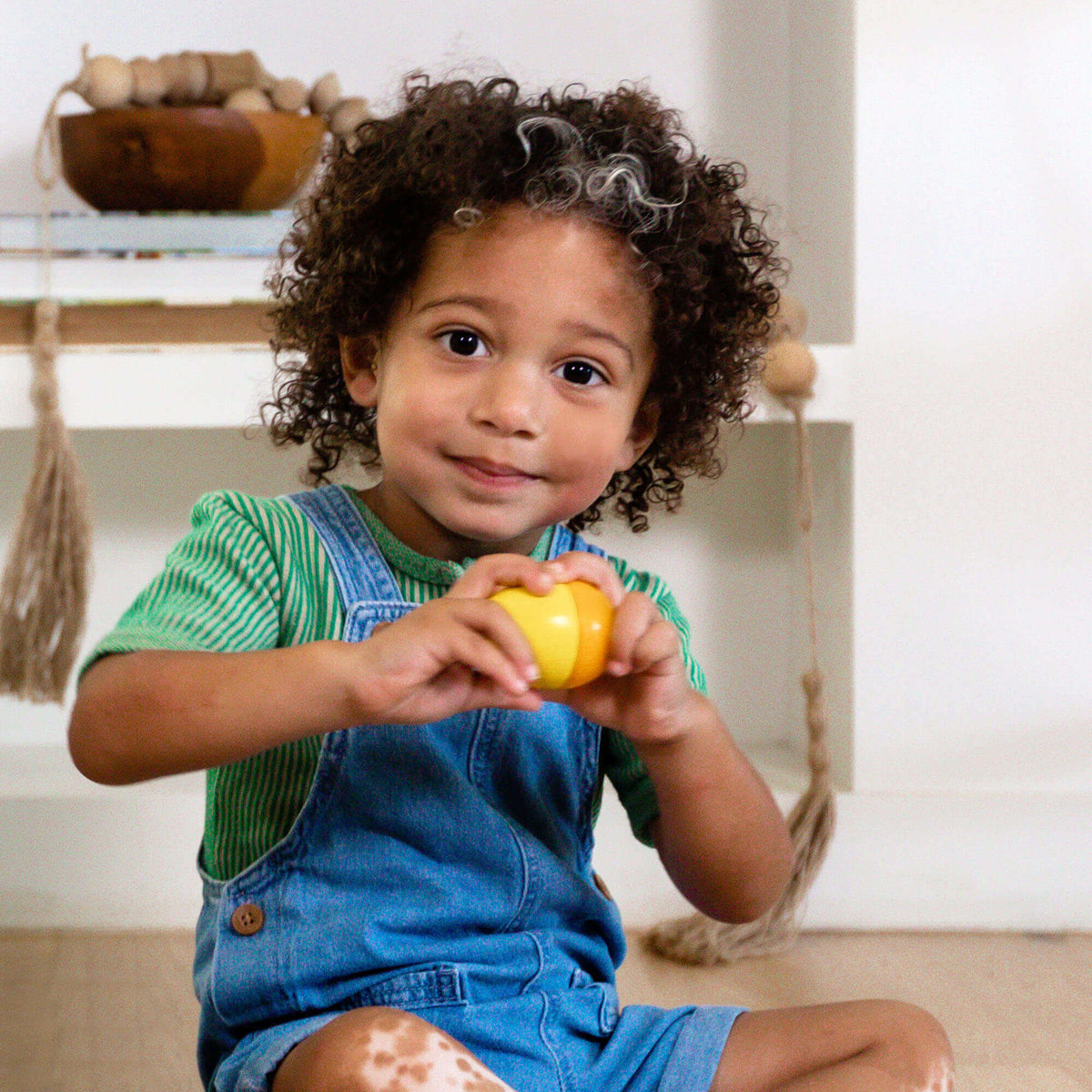 A child holds the yellow Fun With Sounds Wooden Egg.