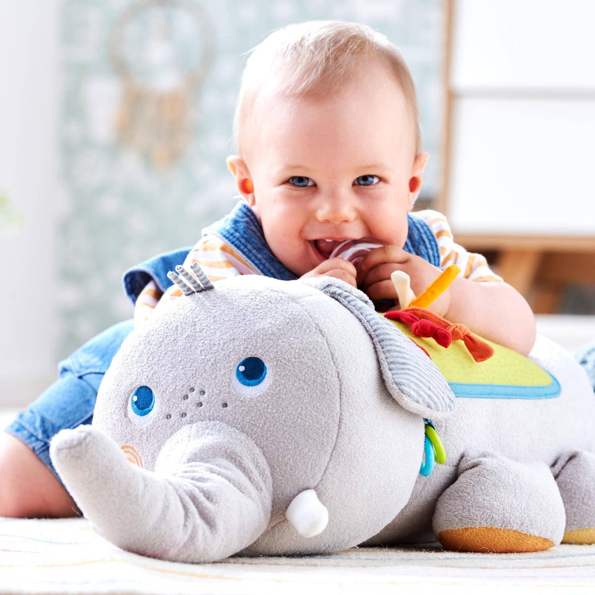 A toddler uses the teething ring on the Baby Elephant Discover Sensory Pillow.