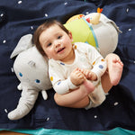 A baby lays back on the Baby Elephant Discovery Sensory Pillow.