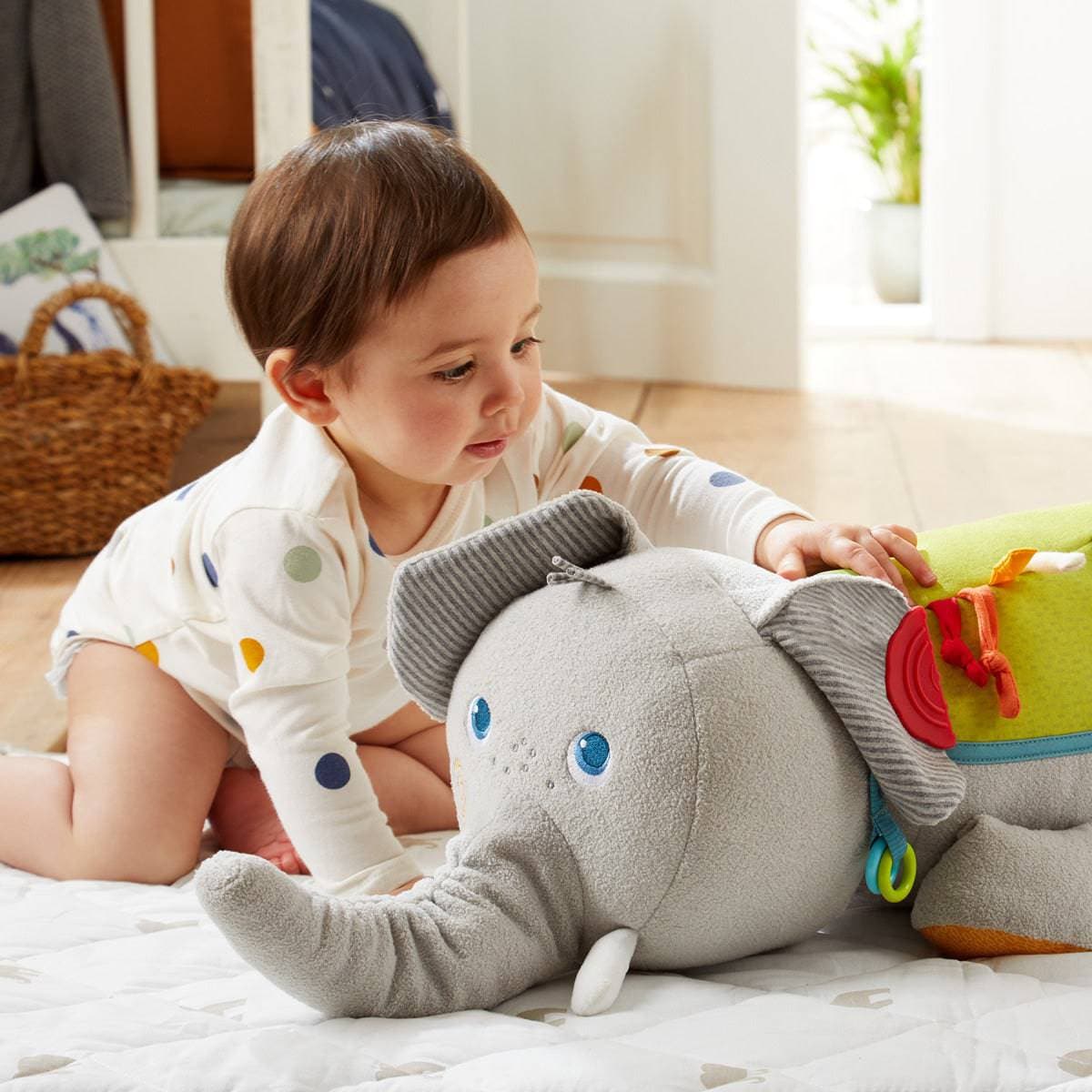 A baby crawls towards the Baby Elephant Discovery Sensory Pillow by HABA.
