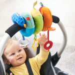 A baby in a car seat looks up at the handle which is decorated in hte Rainbow Activity Spiral Stroller & Car Seat Toy.