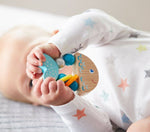 A baby holds up the Rattlefish Baby Wooden Rattle.