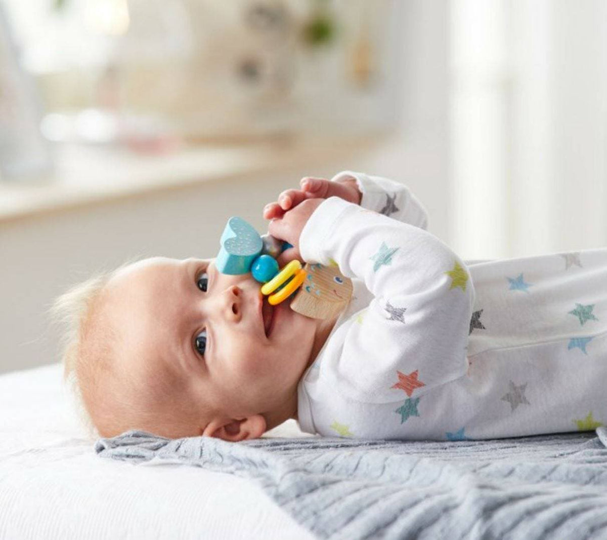 A baby puts the  Rattlefish Baby Wooden Rattle in its mouth.