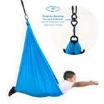 A child looks like they are flying while they lay belly-down in the Blue Harkla Sensory Compression Swing with Swivel.