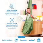 A child stands in the Harkla Green Sensory Compression Swing with Swivel.