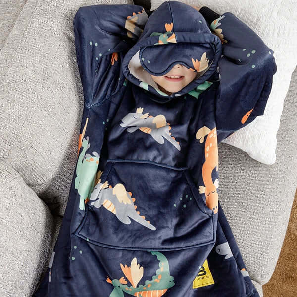 A child lays on a couch with their arms behind their head while resting in their Hideout Hoodie Kids.