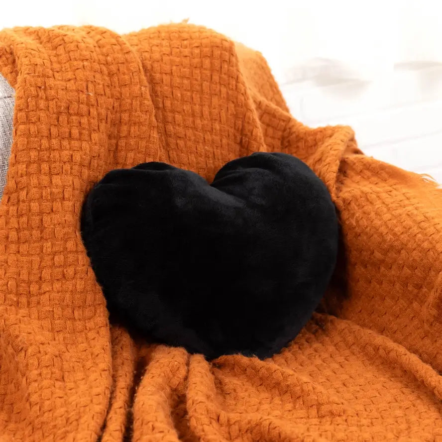 The black Heart to Hug 5 lb Weighted Pillow on an orange blanket.