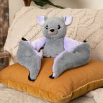 Berkeley the Bat sits with its wings poised on an orange pillow.