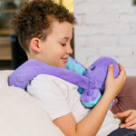 Indigo the Octopus sits on a childs chest with its arms stretched over the shoulders.