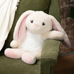 Iggy the Bunny is sitting on a couch with one arm draped over the couch arm.