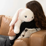 Someone sits on a leather couch while holding Iggy the Bunny over their left shoulder.