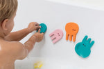 A child pushes a Jellyfish Bath Puzzle piece against the tub.