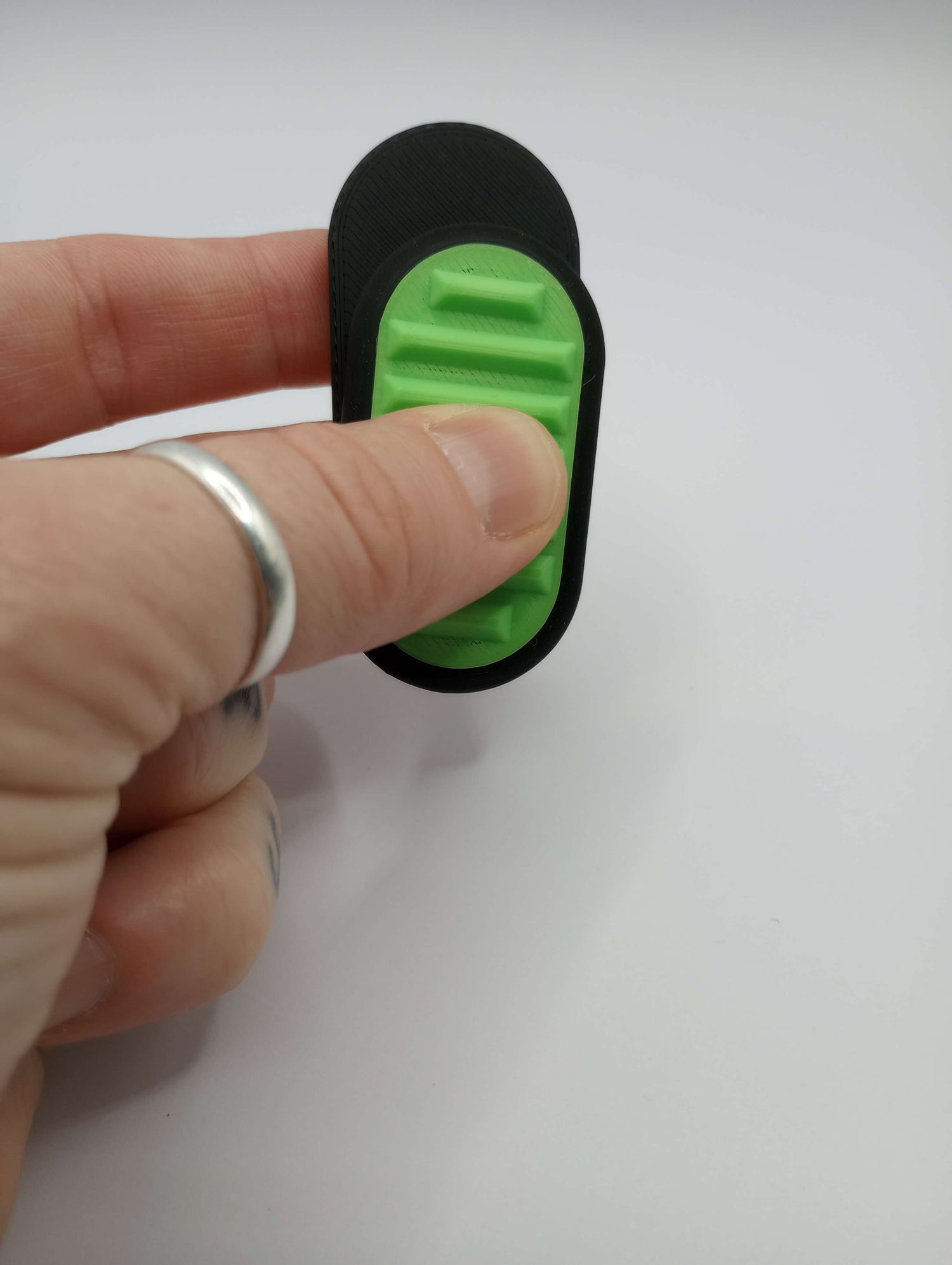 A hand slides the Spiky Silent Fidget Slider, Sensory Tool House Edition.