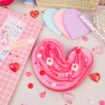 Hogs & Kisses Butter Slime stretched into a heart with two pigs holding hearts placed on top.