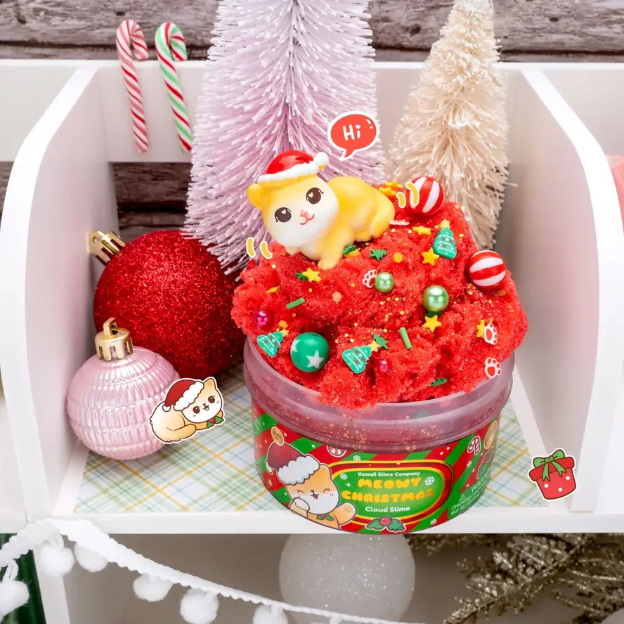 An overflowing Meowy Christmas Cloud Slime sits on a shelf next to cheerful holiday decorations.