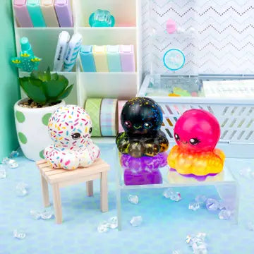 Three Octo-Squish Mini Squishies sit on doll furniture.