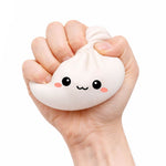 A hand squeezes the white  Lucky Bao Mystery Squishy Dumpling.