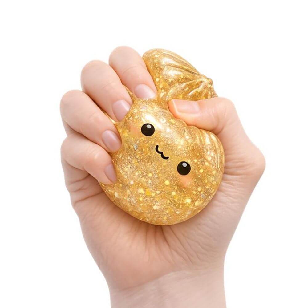 A hand squeezing the golden glittery  Lucky Bao Mystery Squishy Dumpling.