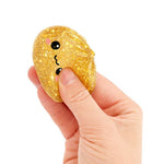A hand squeezes the glittery gold Mini Lucky Bao Mystery Squishy Dumpling.