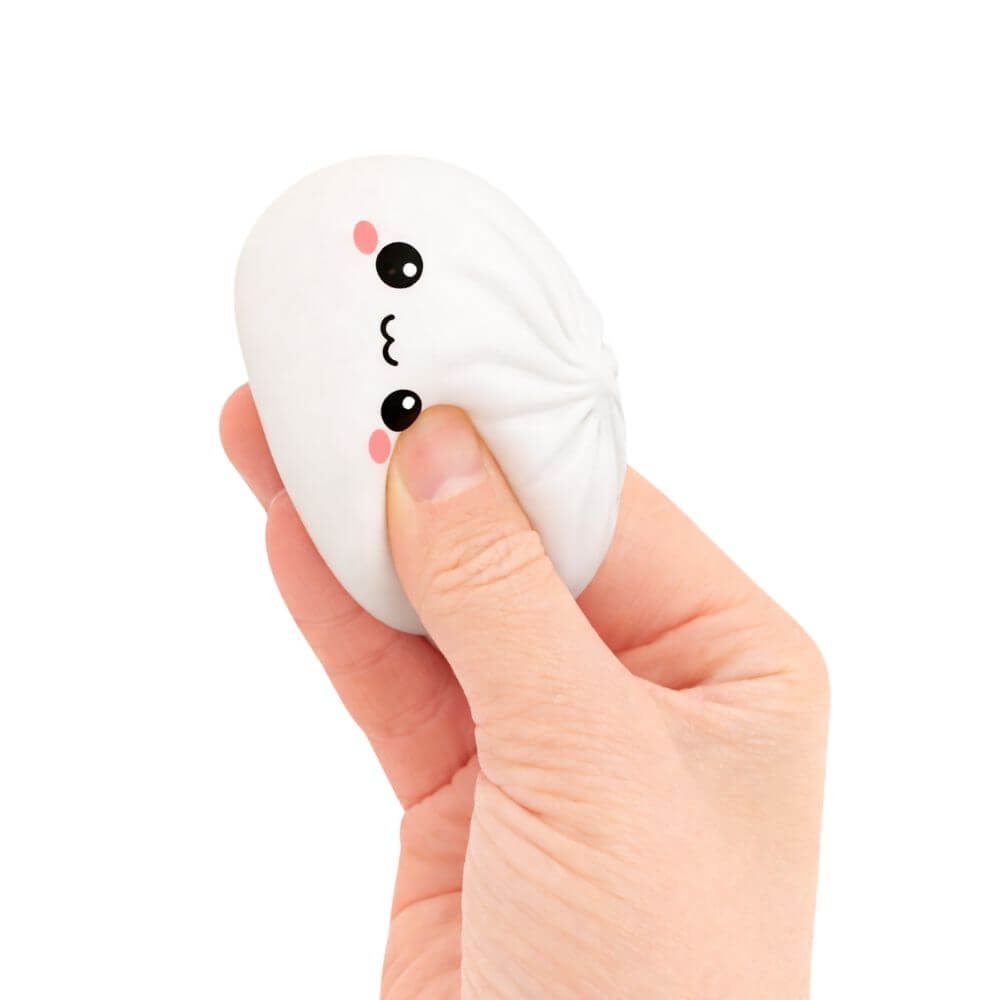 A hand squeezes the white Mini Lucky Bao Mystery Squishy Dumpling.