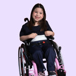 A child in a wheelchair holds up their shirt to reveal the compression undershirt as a part of the Kids Compression Lined Sensory T-shirt.