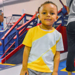 A child at a gym wears the Yellow and Mint Kids Easy-to-See Sensory Friendly T-shirt.