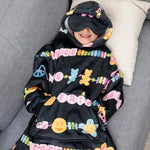 A child models the Kids Friends Forever Hideout Hoodie while laying on a couch, their hands in the kangaroo pocket and the built-in eye mask down.