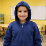 A child grins in a classroom while wearing the Kids QuietSense™ Zippered Sound Reducing Sensory Hoodie in Navy.
