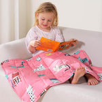 A child reads a book while perched on a couch under thee Kitties Weighted Cooling Lap Pad 2 lb.