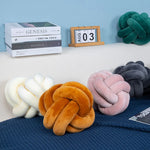 The Knotted Plush Sensory Pillow on a couch.