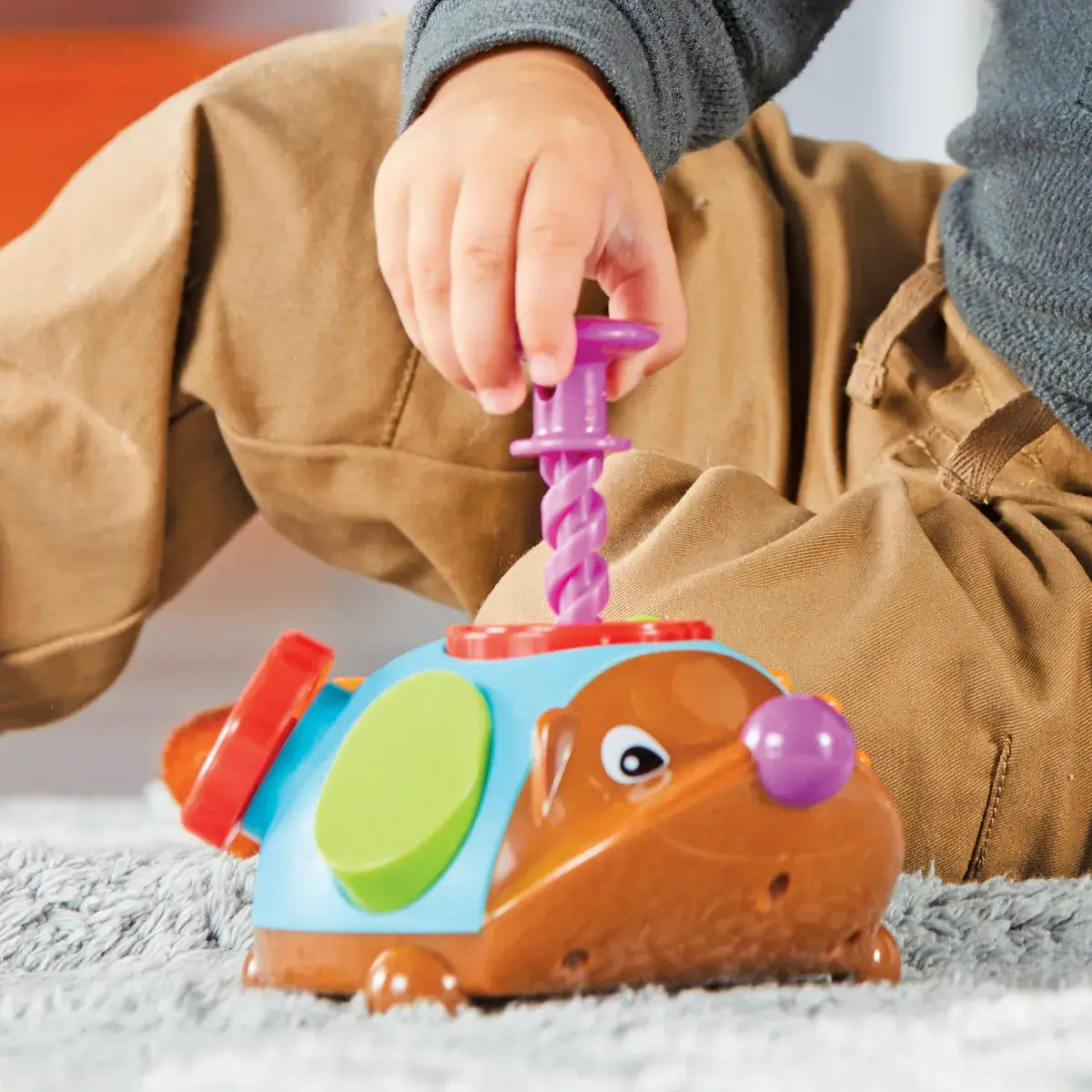 A child pulls a screw out of Spike the Fine Motor Hedgehog Fidget Friend.
