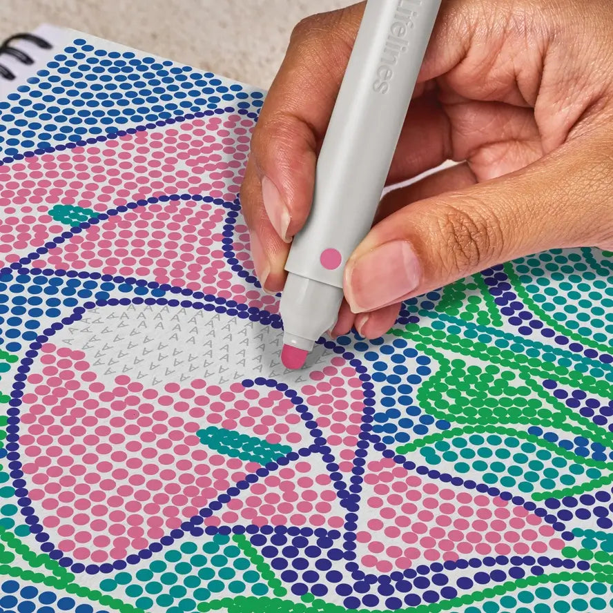 A hand fills in the color pink on the letter A on a design from the Lifelines FlowArt Dot-by-Letter Botanicals pad.