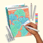 A hand filled in the color blue on a letter on a picture of ginko leaves in the Lifelines FLowArt Dot-by-Letter Botanicals Pad.