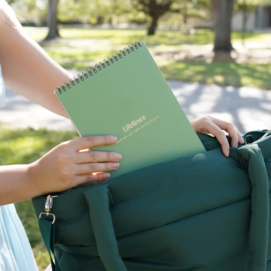 A hand puts a green Lifelines pad into a green bag.