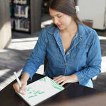 A person sits at a desk, filling in the letters with a corresponding color.