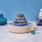 A calm blue scene featuring the Lifelines Stacking Stones Diffuser.
