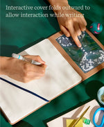 One hand fidgets with the beads in the cover of the "Take Your Time" Tactile Sensory Journal while the other writes on an embossed page.