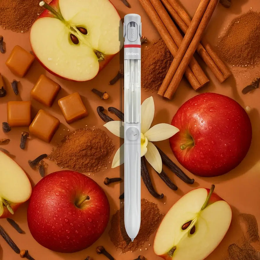 The Lifelines Pen Diffuser in front of a background of caramel, cinnamon sticks, vanilla beans, and apples.